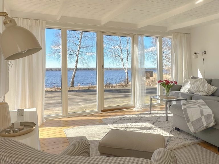 Helles Wohnzimmer mit großer Fensterfront und Blick auf den See in verschneiter Landschaft.